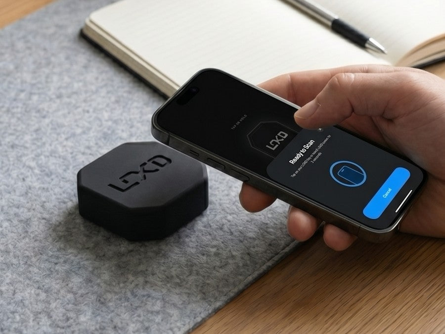 A LOKD Key on a desk beside a phone showing the scan screen
